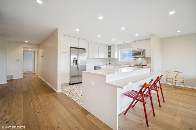 407 Ashland Ave Unit 6H, River Forest, IL 60305 - kitchen with appliances with stainless steel finishes, a center island, baseboards, light countertops, and a kitchen bar
