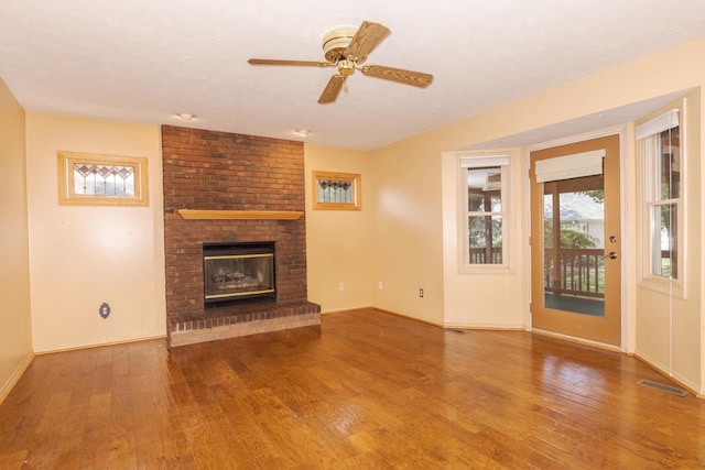 2321 Woodhavens Dr, Bloomington, IL 61701 - unfurnished living room featuring wood finished floors, a brick fireplace, and ceiling fan