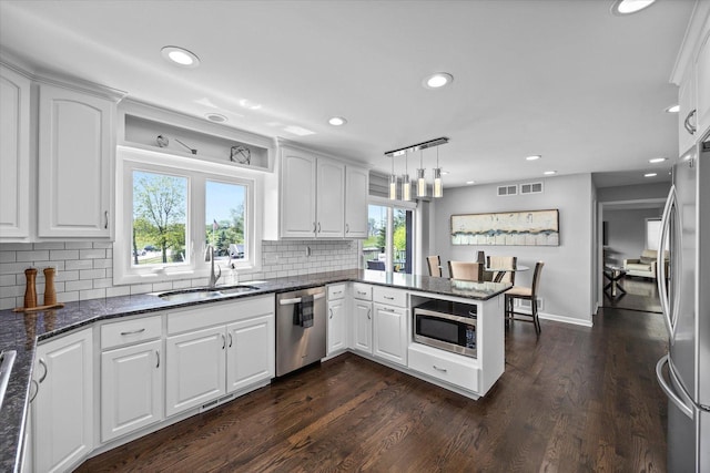 7 Surrey Rd, Lemont, IL 60439 - kitchen featuring stainless steel appliances, a sink, a peninsula, decorative backsplash, and dark stone countertops
