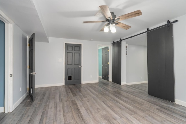 817 N Mohave Dr, Pontiac, IL 61764 - unfurnished bedroom featuring a barn door, wood finished floors, baseboards, and a ceiling fan