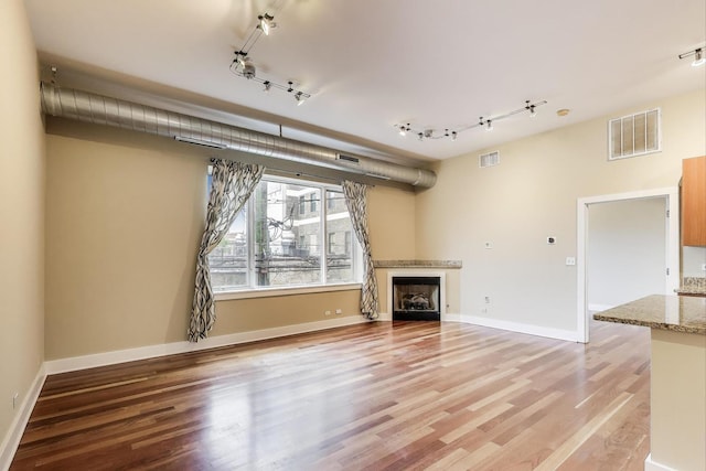 4751 N Artesian Ave Unit 206, Chicago, IL 60625 - unfurnished living room featuring rail lighting, a fireplace, and light wood-style floors