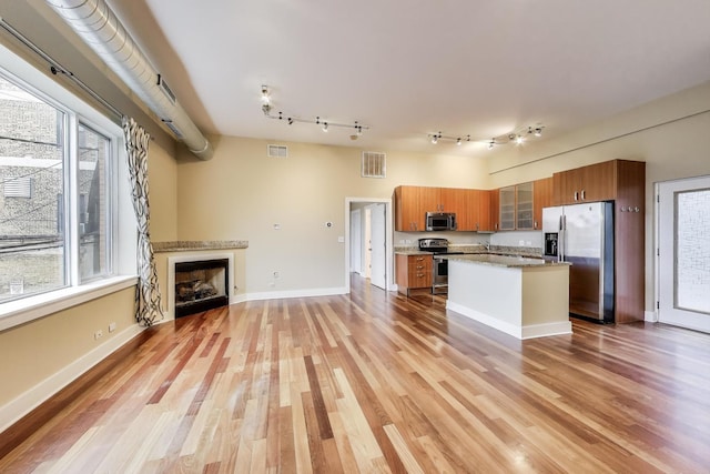 4751 N Artesian Ave Unit 206, Chicago, IL 60625 - kitchen with appliances with stainless steel finishes, brown cabinets, light wood-style flooring, and glass insert cabinets