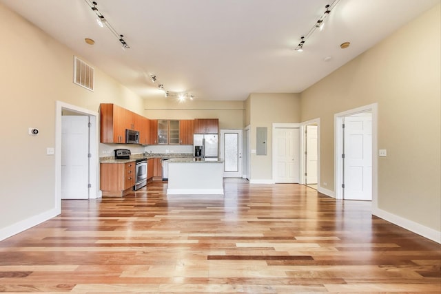 4751 N Artesian Ave Unit 206, Chicago, IL 60625 - kitchen featuring stainless steel appliances, rail lighting, brown cabinets, light wood-type flooring, and a towering ceiling
