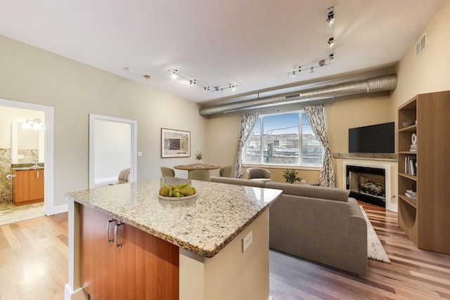 4751 N Artesian Ave Unit 206, Chicago, IL 60625 - kitchen featuring light wood-style floors, a kitchen island, light stone countertops, and a fireplace