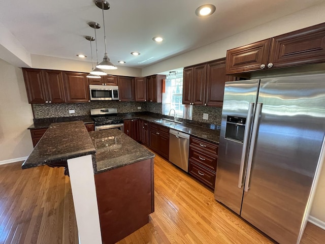 13153 W Pin Oak Dr, Homer Glen, IL 60491 - kitchen featuring appliances with stainless steel finishes, a sink, decorative backsplash, decorative light fixtures, and light wood-style flooring