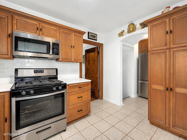 82 Northgate Rd, Riverside, IL 60546 - kitchen with appliances with stainless steel finishes, arched walkways, light countertops, and brown cabinets