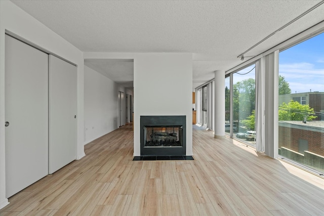 3120 S Indiana Ave Unit 207, Chicago, IL 60616 - unfurnished living room with floor to ceiling windows, wood finished floors, a multi sided fireplace, and a textured ceiling