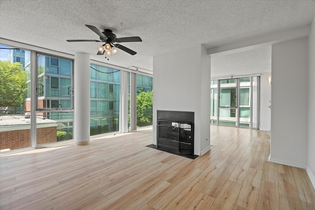 3120 S Indiana Ave Unit 207, Chicago, IL 60616 - unfurnished living room with wood finished floors, expansive windows, a ceiling fan, a textured ceiling, and a multi sided fireplace