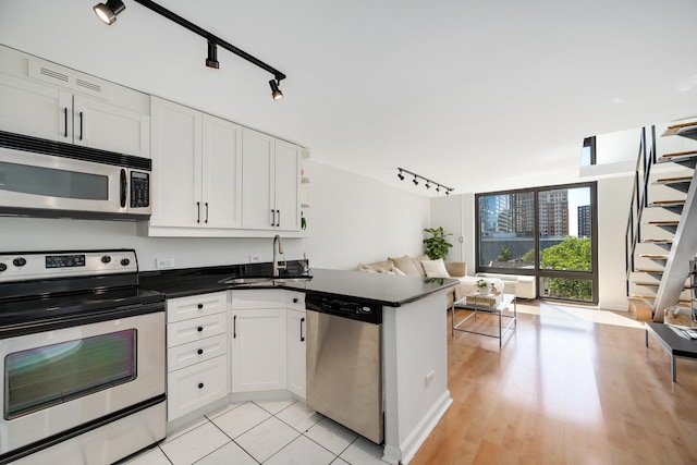 1221 N Dearborn St Unit 601S, Chicago, IL 60610 - kitchen with stainless steel appliances, open floor plan, a sink, track lighting, and dark countertops