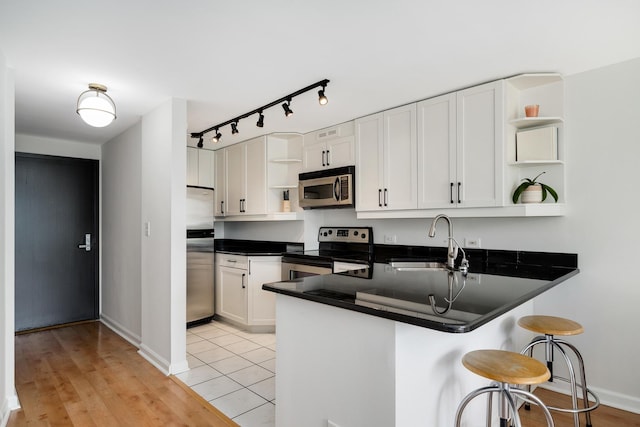 1221 N Dearborn St Unit 601S, Chicago, IL 60610 - kitchen with open shelves, stainless steel appliances, a sink, a peninsula, and dark countertops