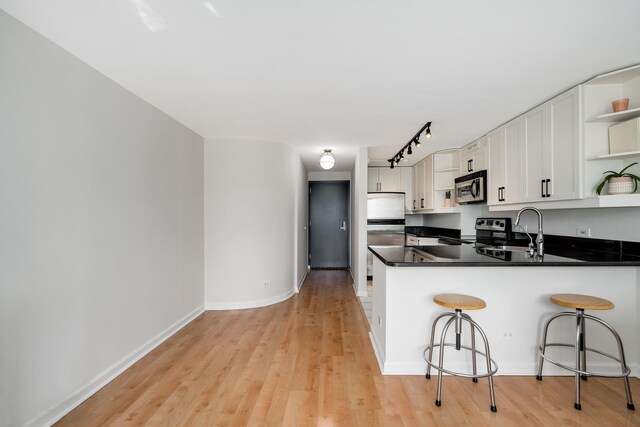 1221 N Dearborn St Unit 601S, Chicago, IL 60610 - kitchen featuring open shelves, stainless steel appliances, a sink, a peninsula, and light wood-style floors