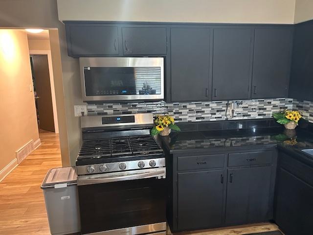 746 May St, Calumet City, IL 60409 - kitchen featuring stainless steel appliances, light wood-style floors, tasteful backsplash, dark countertops, and baseboards