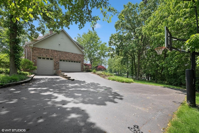 26874 N Countryside Lake Dr, Mundelein, IL 60060 - view of side of home with asphalt driveway, brick siding, a garage, and a chimney