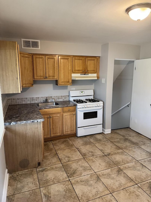 2219 S 13th Ave, Broadview, IL 60155 - kitchen with white range with gas stovetop, under cabinet range hood, a sink, and brown cabinetry