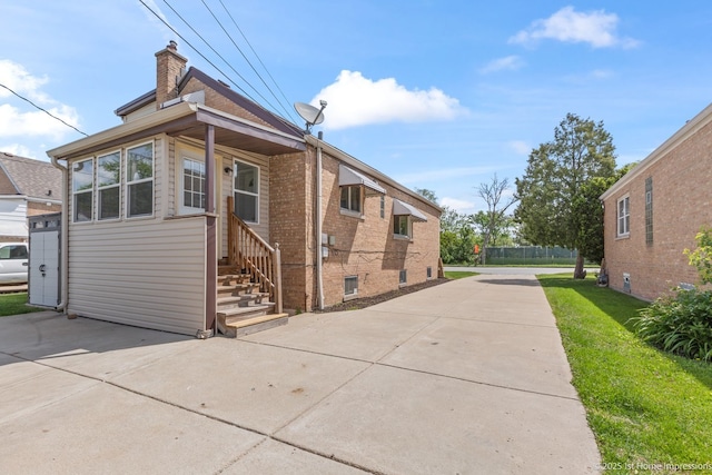 2312 S 1st Ave, North Riverside, IL 60546 - view of side of home with a chimney, a yard, brick siding, and concrete driveway