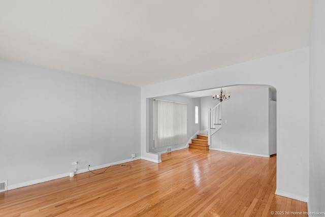 2312 S 1st Ave, North Riverside, IL 60546 - unfurnished room with a chandelier, light wood-type flooring, stairs, baseboards, and arched walkways