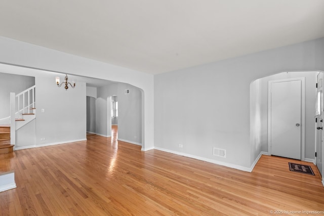 2312 S 1st Ave, North Riverside, IL 60546 - unfurnished living room with arched walkways, light wood-style floors, stairway, a chandelier, and baseboards