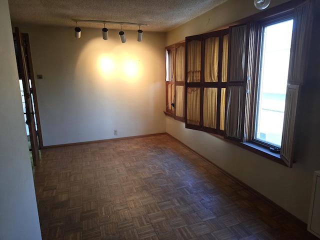 3905 N Oak Park Ave, Chicago, IL 60634 - unfurnished room featuring healthy amount of natural light, track lighting, a textured ceiling, and baseboards