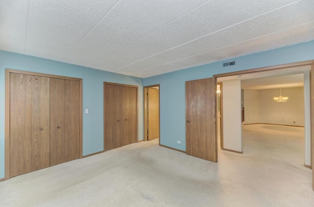 464 S President St Unit 101, Carol Stream, IL 60188 - unfurnished bedroom featuring a chandelier, carpet floors, multiple closets, and a textured ceiling