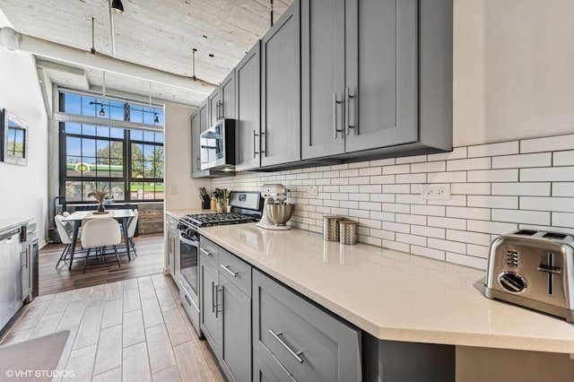 3963 W Belmont Ave Unit 140, Chicago, IL 60618 - kitchen featuring appliances with stainless steel finishes, gray cabinetry, and backsplash