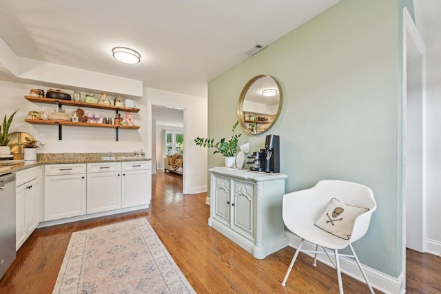 324 W Crystal Lake Ave, Crystal Lake, IL 60014 - kitchen with open shelves, light stone counters, light wood-style floors, white cabinets, and stainless steel dishwasher