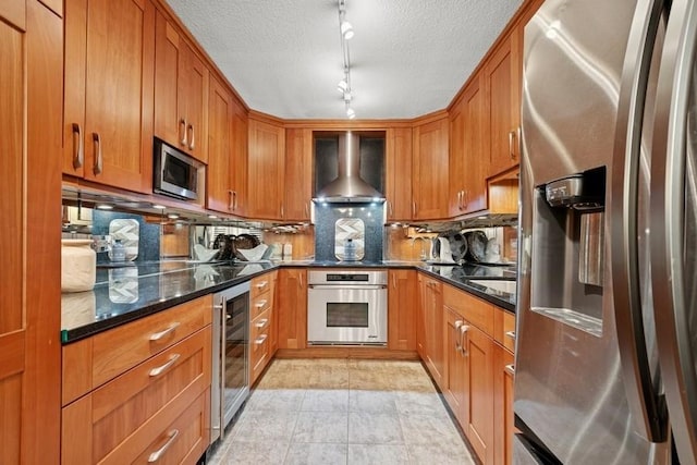 1430 N Astor St Unit 11C, Chicago, IL 60610 - kitchen with appliances with stainless steel finishes, beverage cooler, wall chimney range hood, brown cabinetry, and a textured ceiling