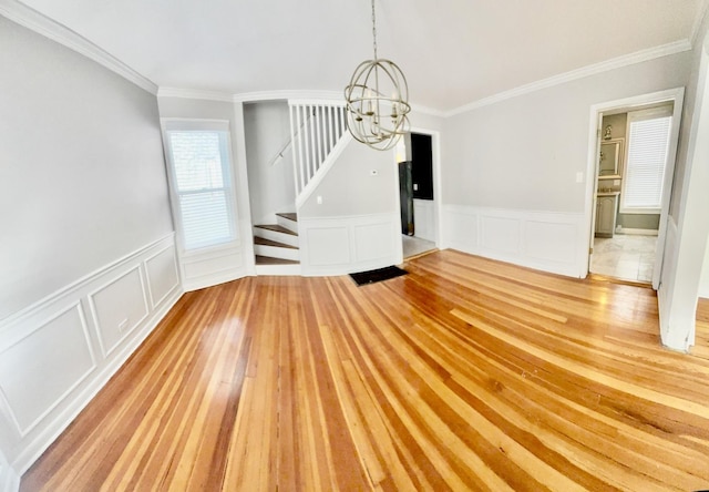4118 N Kedzie Ave, Chicago, IL 60618 - unfurnished dining area with a chandelier, stairs, ornamental molding, wainscoting, and light wood-type flooring
