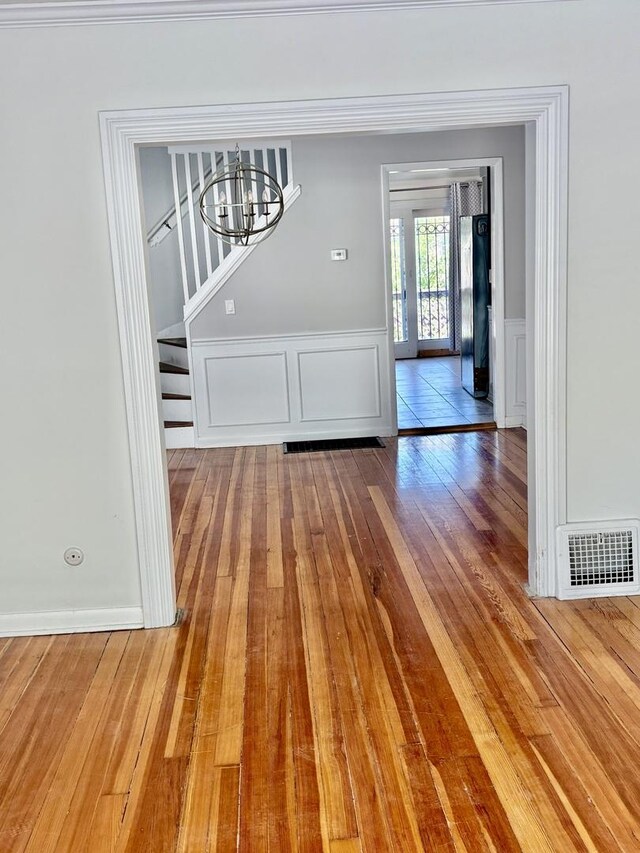 4118 N Kedzie Ave, Chicago, IL 60618 - unfurnished dining area featuring hardwood / wood-style flooring, a chandelier, a decorative wall, wainscoting, and stairs