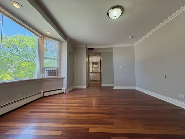 8232 Niles Center Rd Unit 317, Skokie, IL 60077 - unfurnished room featuring ornamental molding, wood finished floors, baseboards, cooling unit, and a baseboard heating unit