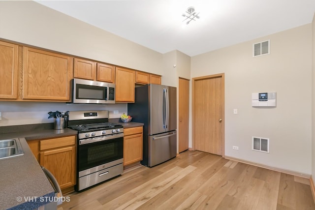 6417 Blue Sky Ln, Matteson, IL 60443 - kitchen featuring stainless steel appliances, light wood-style floors, dark countertops, a sink, and baseboards
