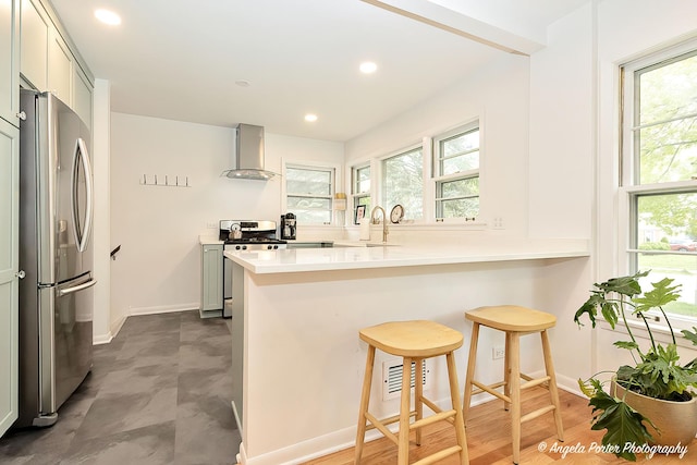 10067 Lavergne Ave, Skokie, IL 60077 - kitchen featuring stainless steel appliances, wall chimney exhaust hood, a peninsula, a breakfast bar area, and baseboards