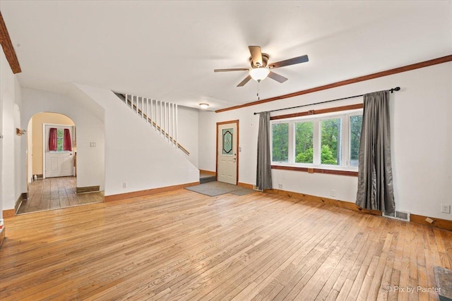 119 W S Ave, Spring Grove, IL 60081 - unfurnished living room with light wood finished floors, a ceiling fan, stairway, arched walkways, and baseboards