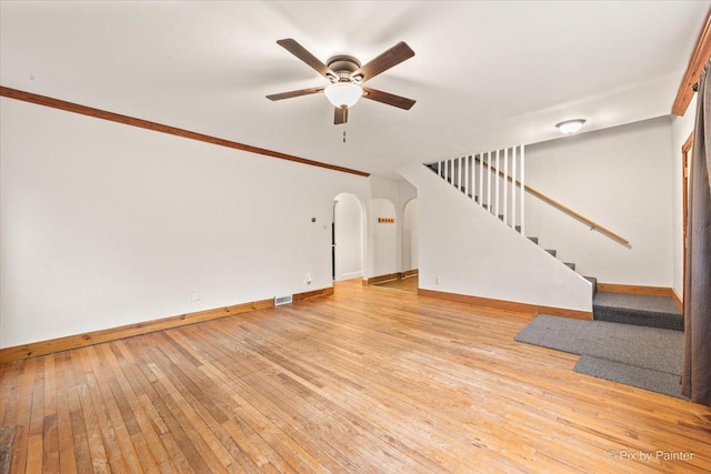 119 W S Ave, Spring Grove, IL 60081 - unfurnished living room featuring ceiling fan, arched walkways, light wood finished floors, baseboards, and stairway