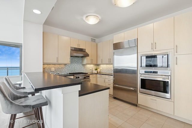 600 N Lake Shore Dr Unit 3411, Chicago, IL 60611 - kitchen with built in appliances, under cabinet range hood, a peninsula, cream cabinetry, and dark countertops