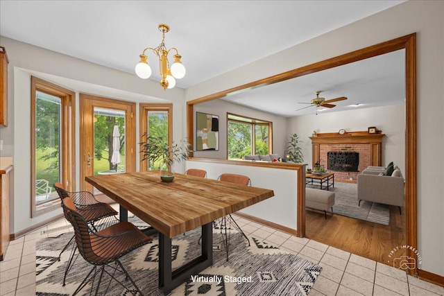 560 Braemar Ave, Naperville, IL 60563 - dining space with light tile patterned floors, a brick fireplace, a chandelier, and ceiling fan
