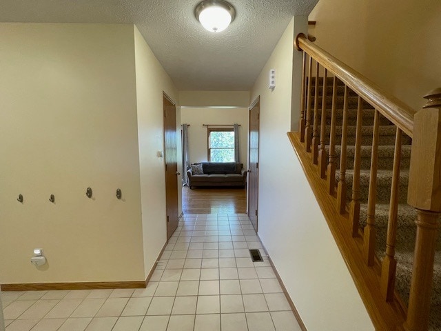 1181 Golf Ct, Dekalb, IL 60115 - hall featuring a textured ceiling, light tile patterned flooring, stairway, and baseboards