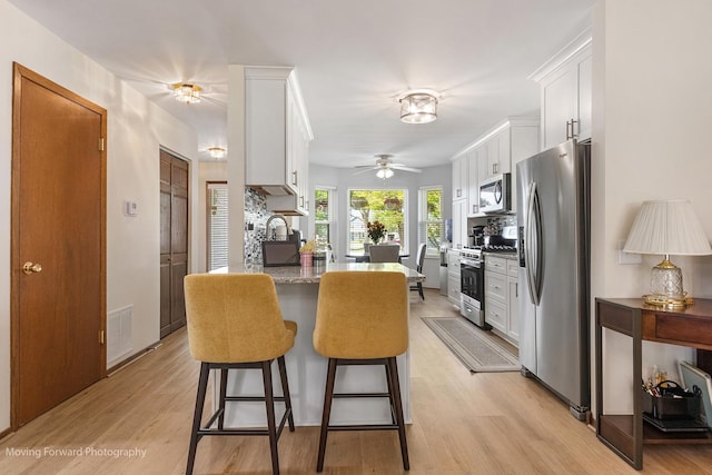 150 Meadows Ct, Sugar Grove, IL 60554 - kitchen featuring appliances with stainless steel finishes, a breakfast bar area, white cabinetry, and light wood-style floors