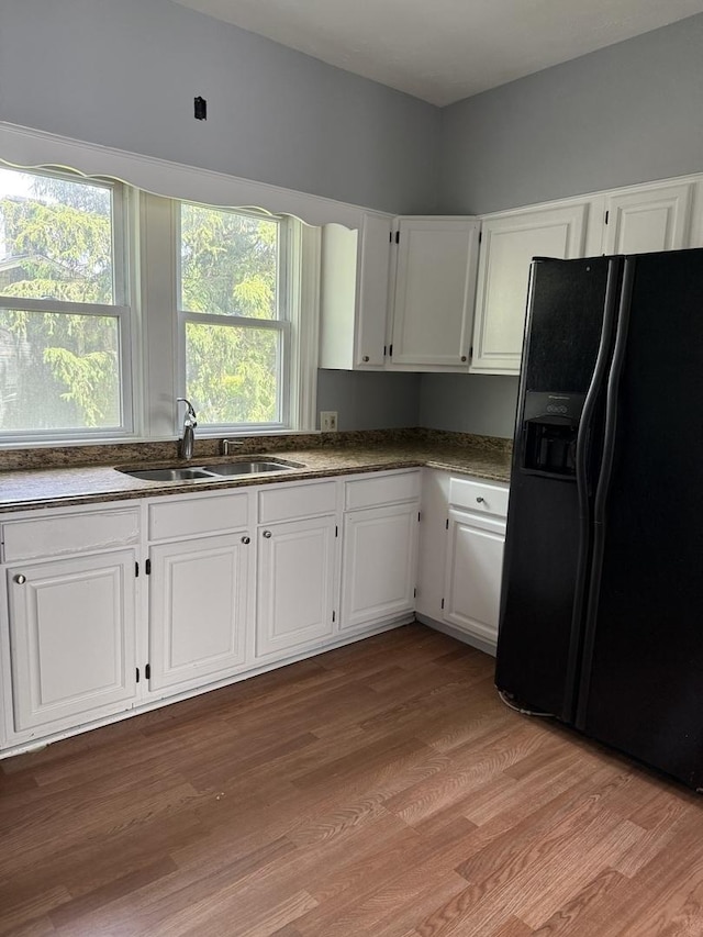 509 S May St, Joliet, IL 60436 - kitchen with black fridge with ice dispenser, a sink, white cabinets, and light wood finished floors