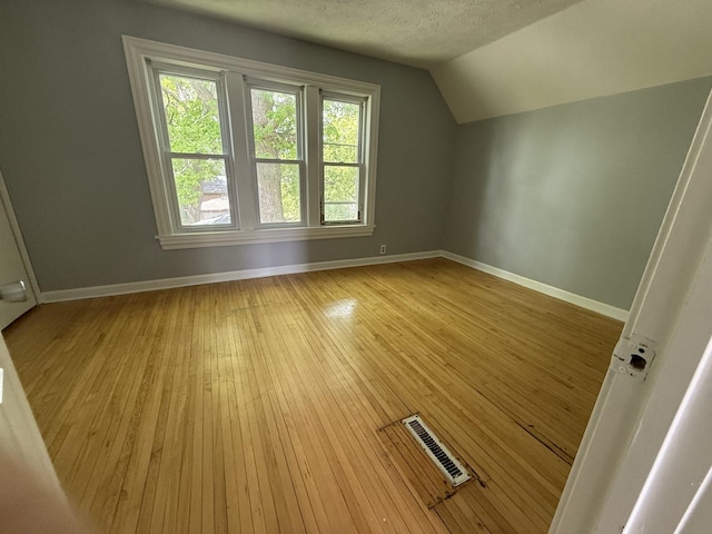 509 S May St, Joliet, IL 60436 - additional living space with lofted ceiling, baseboards, light wood-style floors, and a textured ceiling