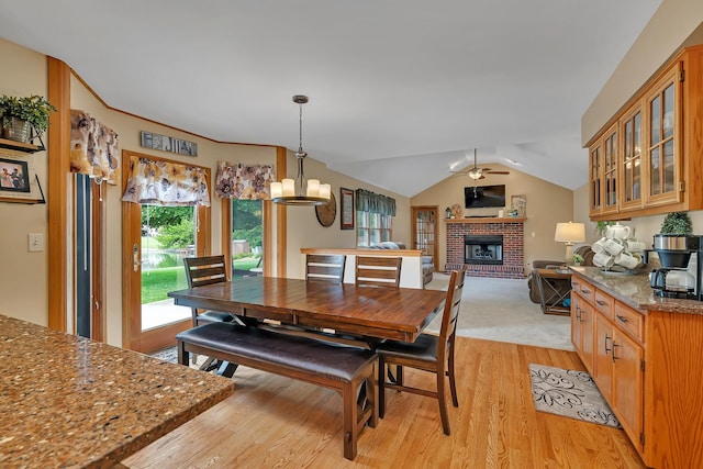 605 Feeney Dr, Minooka, IL 60447 - dining area featuring light wood-type flooring, a fireplace, a ceiling fan, vaulted ceiling, and a chandelier