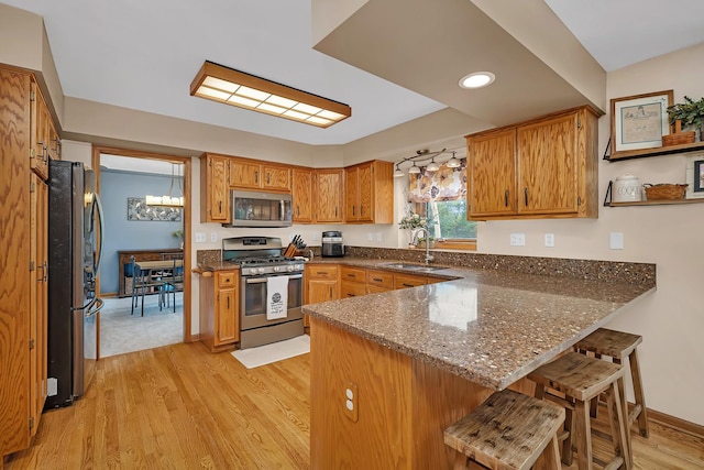 605 Feeney Dr, Minooka, IL 60447 - kitchen featuring stainless steel appliances, a peninsula, a sink, light wood-style flooring, and brown cabinets