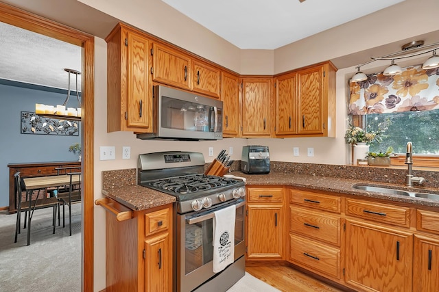 605 Feeney Dr, Minooka, IL 60447 - kitchen featuring appliances with stainless steel finishes, a sink, dark stone countertops, brown cabinets, and light colored carpet