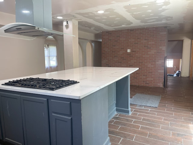 3400 N Buffalo Grove Rd, Arlington Heights, IL 60004 - kitchen with island range hood, black gas stovetop, healthy amount of natural light, light stone counters, and brick wall
