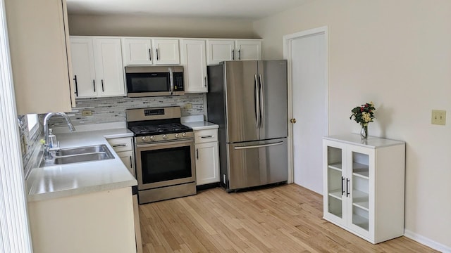 653 Fairview Ln, South Elgin, IL 60177 - kitchen featuring appliances with stainless steel finishes, a sink, decorative backsplash, light wood-type flooring, and white cabinetry