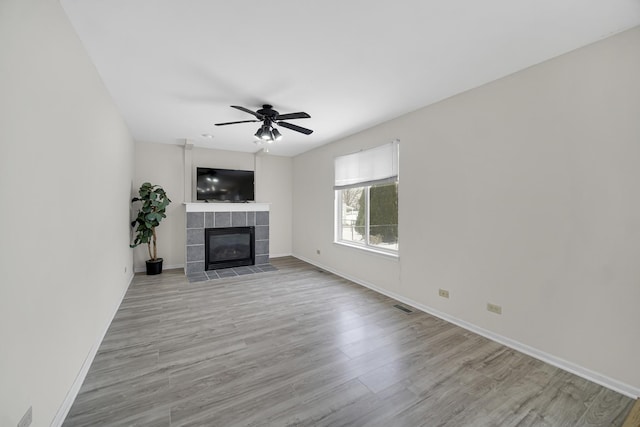 653 Fairview Ln, South Elgin, IL 60177 - unfurnished living room with light wood finished floors, a tiled fireplace, baseboards, and ceiling fan