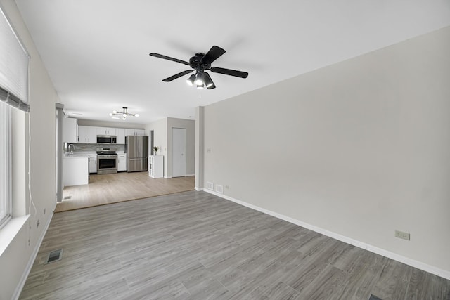 653 Fairview Ln, South Elgin, IL 60177 - unfurnished living room with a ceiling fan, baseboards, light wood-style floors, and a chandelier
