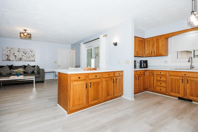 203 S Hershey Rd, Bloomington, IL 61704 - kitchen featuring a sink, light wood-style flooring, brown cabinets, a peninsula, and light countertops