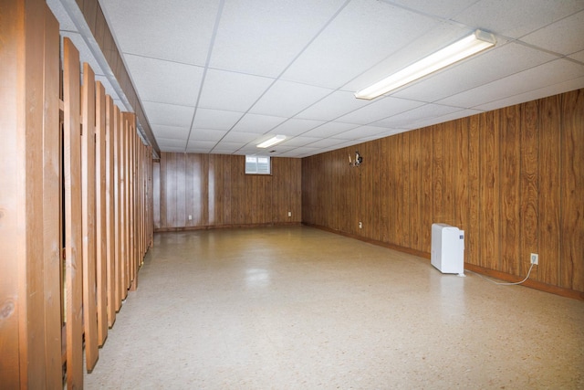 203 S Hershey Rd, Bloomington, IL 61704 - below grade area with baseboards, wood walls, a paneled ceiling, and light floors