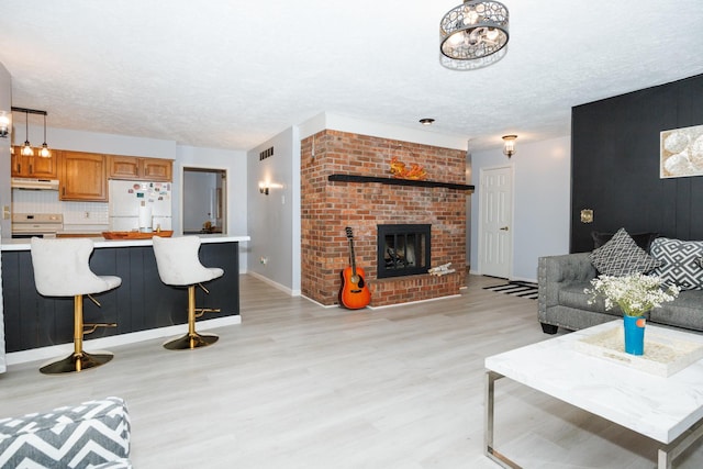203 S Hershey Rd, Bloomington, IL 61704 - living room with light wood-type flooring, a textured ceiling, a fireplace, and baseboards