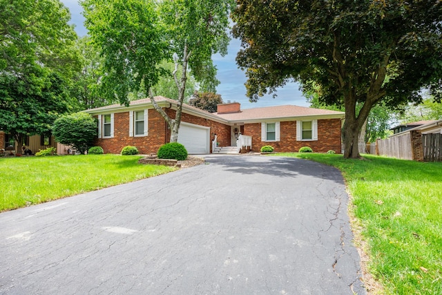 203 S Hershey Rd, Bloomington, IL 61704 - single story home featuring a garage, brick siding, asphalt driveway, and a chimney
